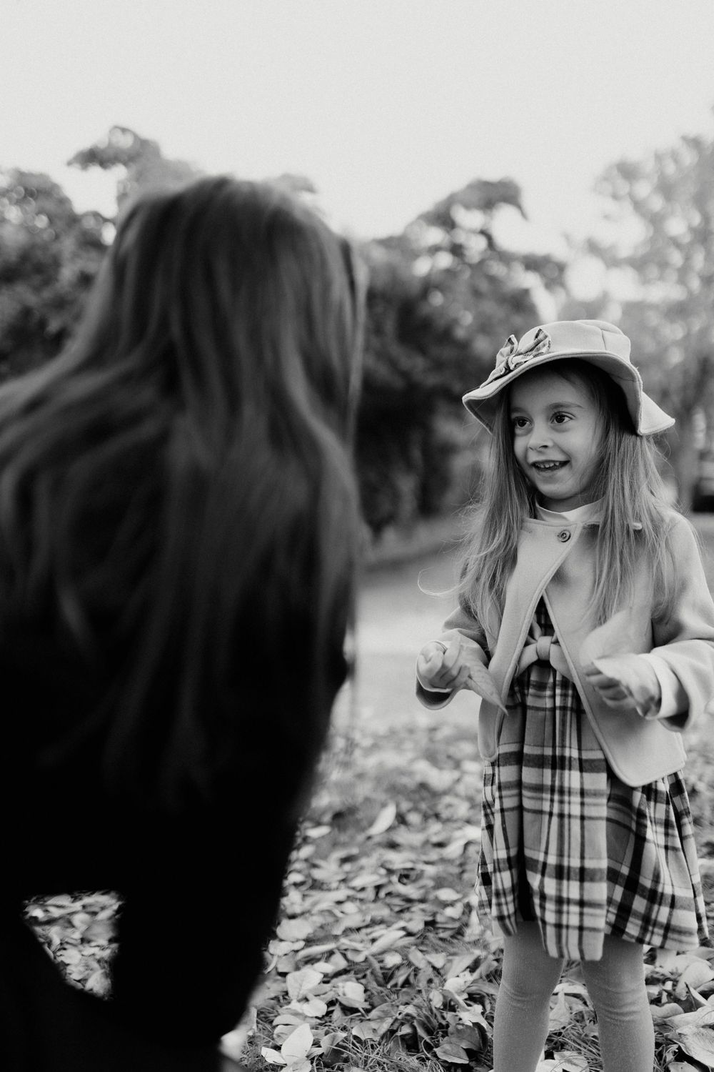 A series of black and white photos showing a child in plaid playing outdoors among fallen autumn leaves.