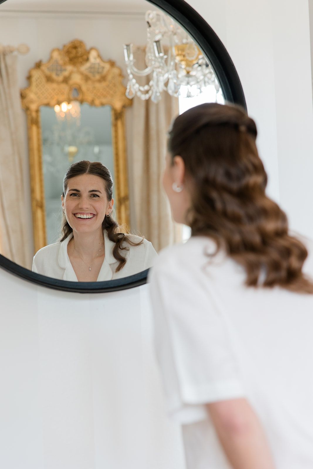A series of mirror reflections showing someone in a white dress getting ready in an elegant room with gold accents.