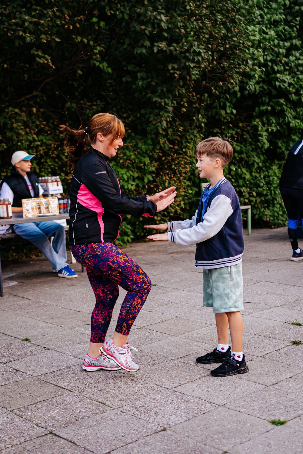 A sequence of images showing two people performing a mirrored exercise routine on a paved outdoor path.