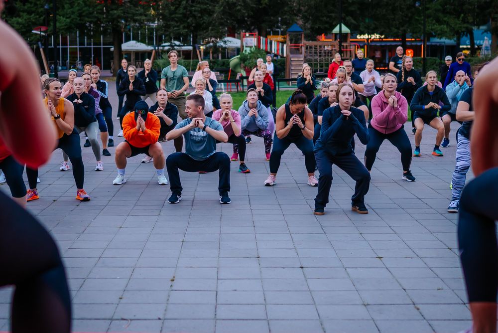 Large group of people exercising together in a public square during an outdoor fitness class.