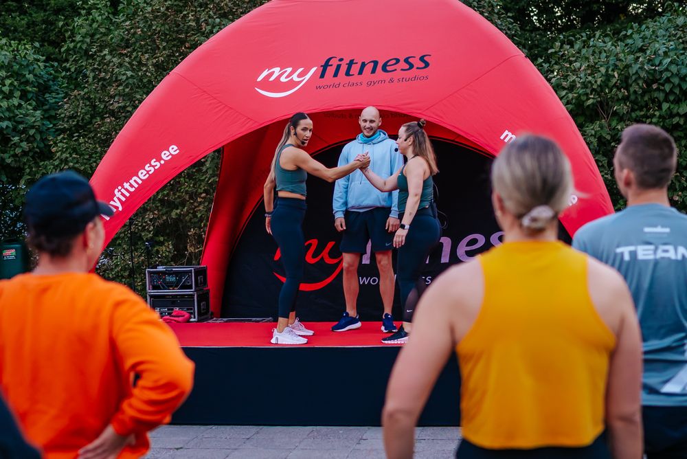 Red inflatable fitness dome setup in an outdoor park setting with participants gathering around it.