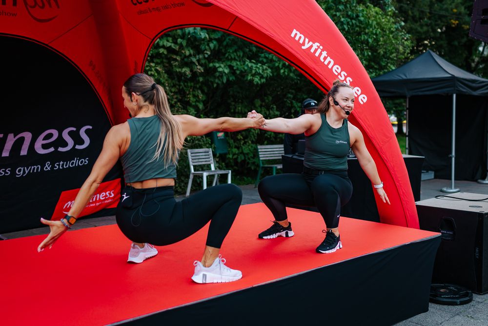 People working out on red fitness mats during an outdoor group exercise class.