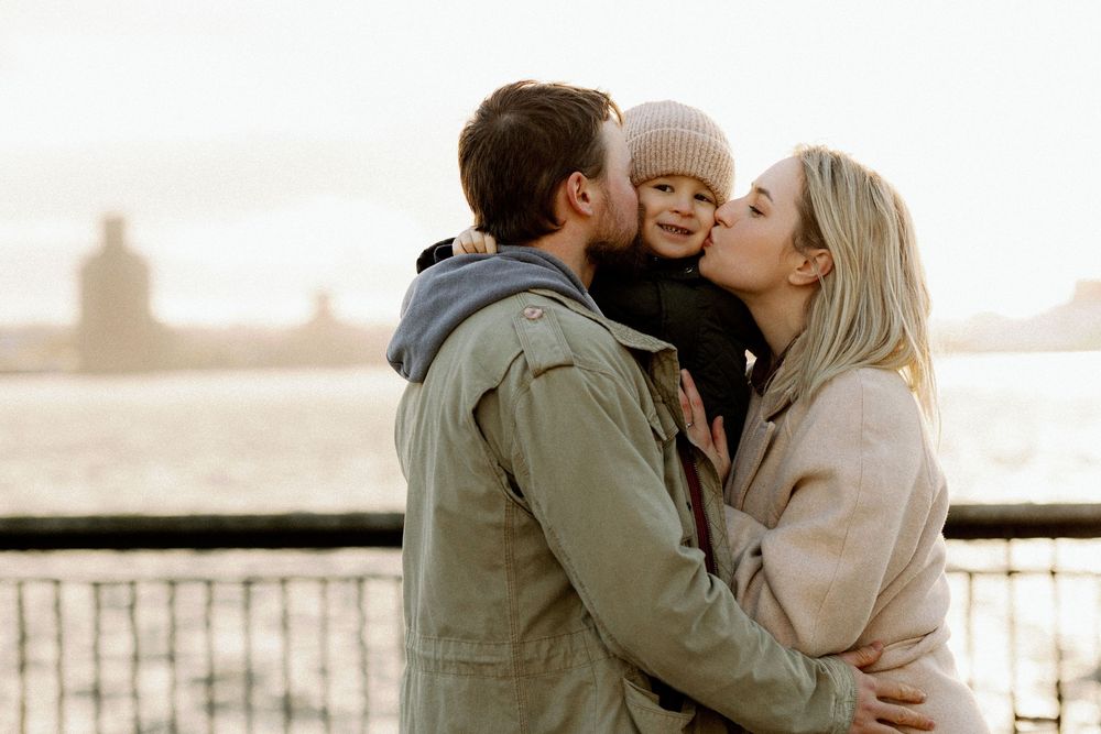 A romantic couple sharing tender kisses in a series of sunset photos by a waterfront railing.