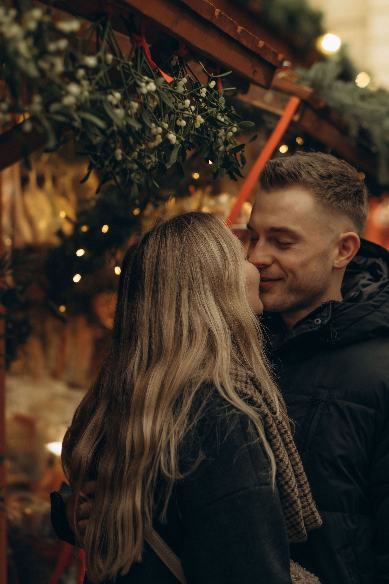 couple kissing under mistletoe at Christmas market in Gamla Stan while being captured by best couple photographer in Stockholm
