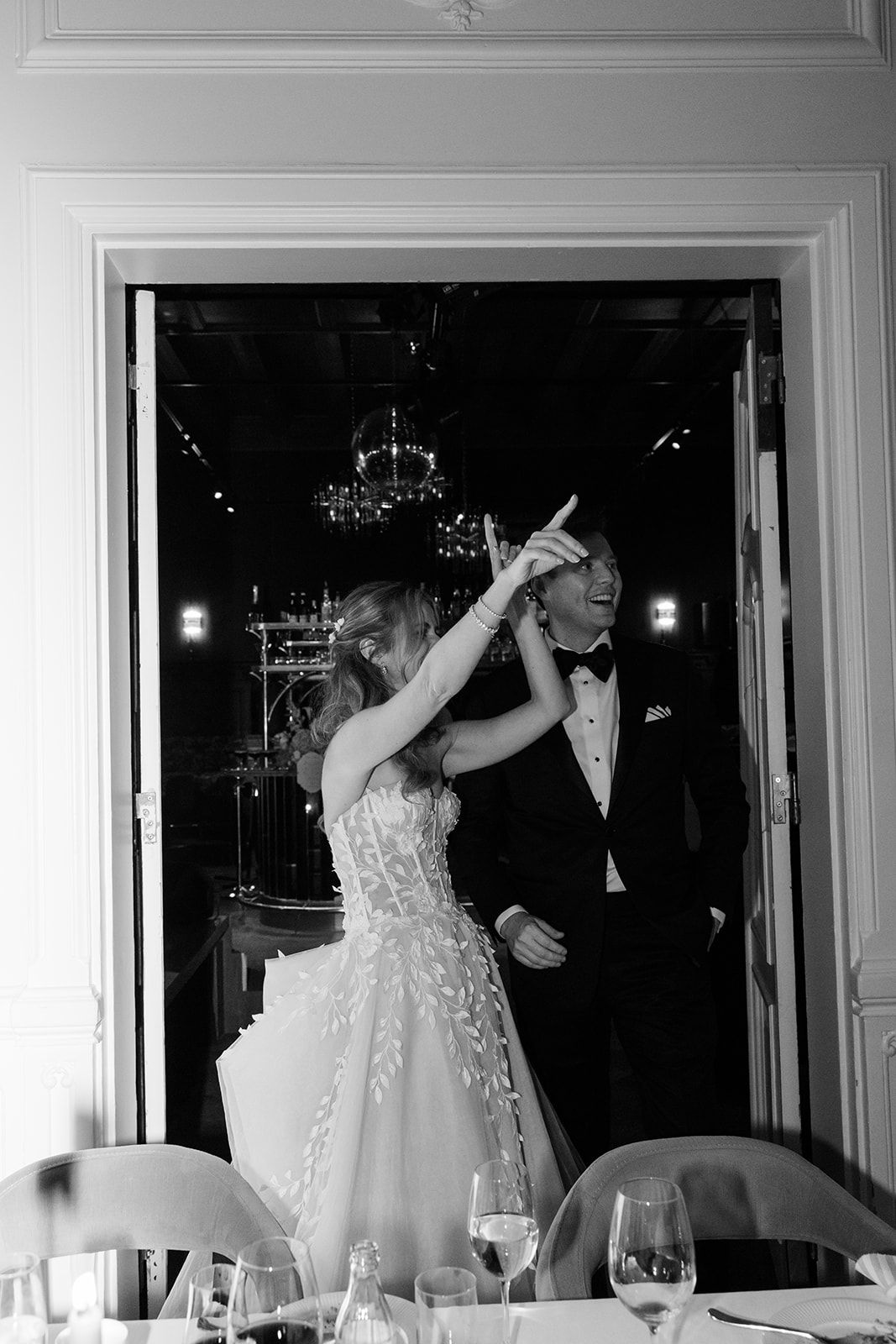 A couple dancing together at an elegant reception venue in black and white photography.
