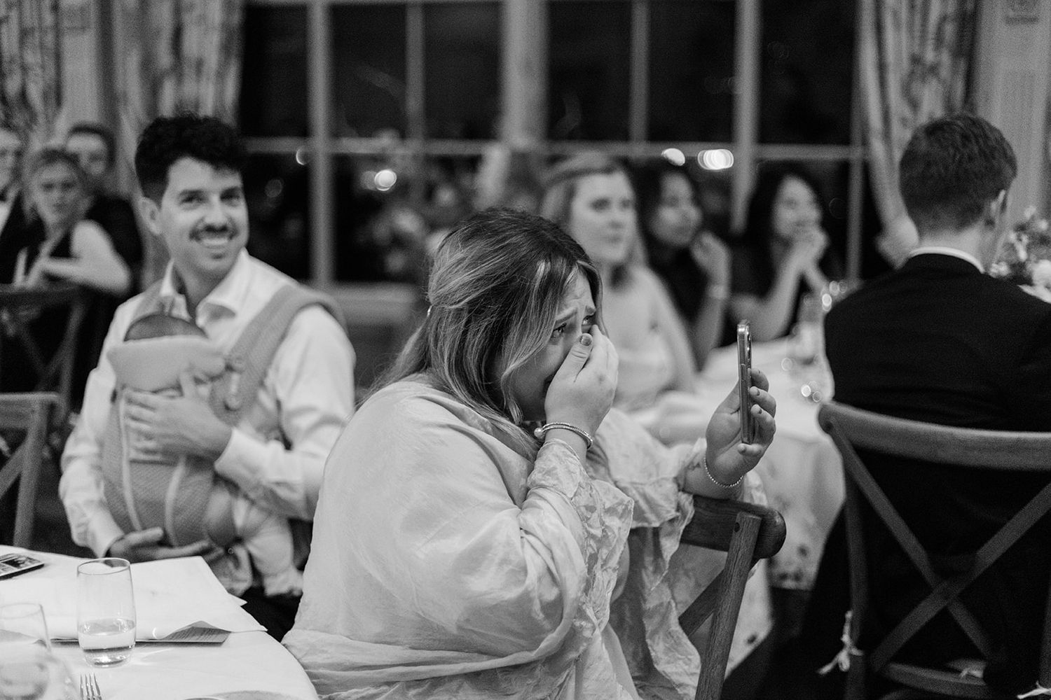 Wedding guests laugh and smile during a joyful reception celebration at an elegant venue.