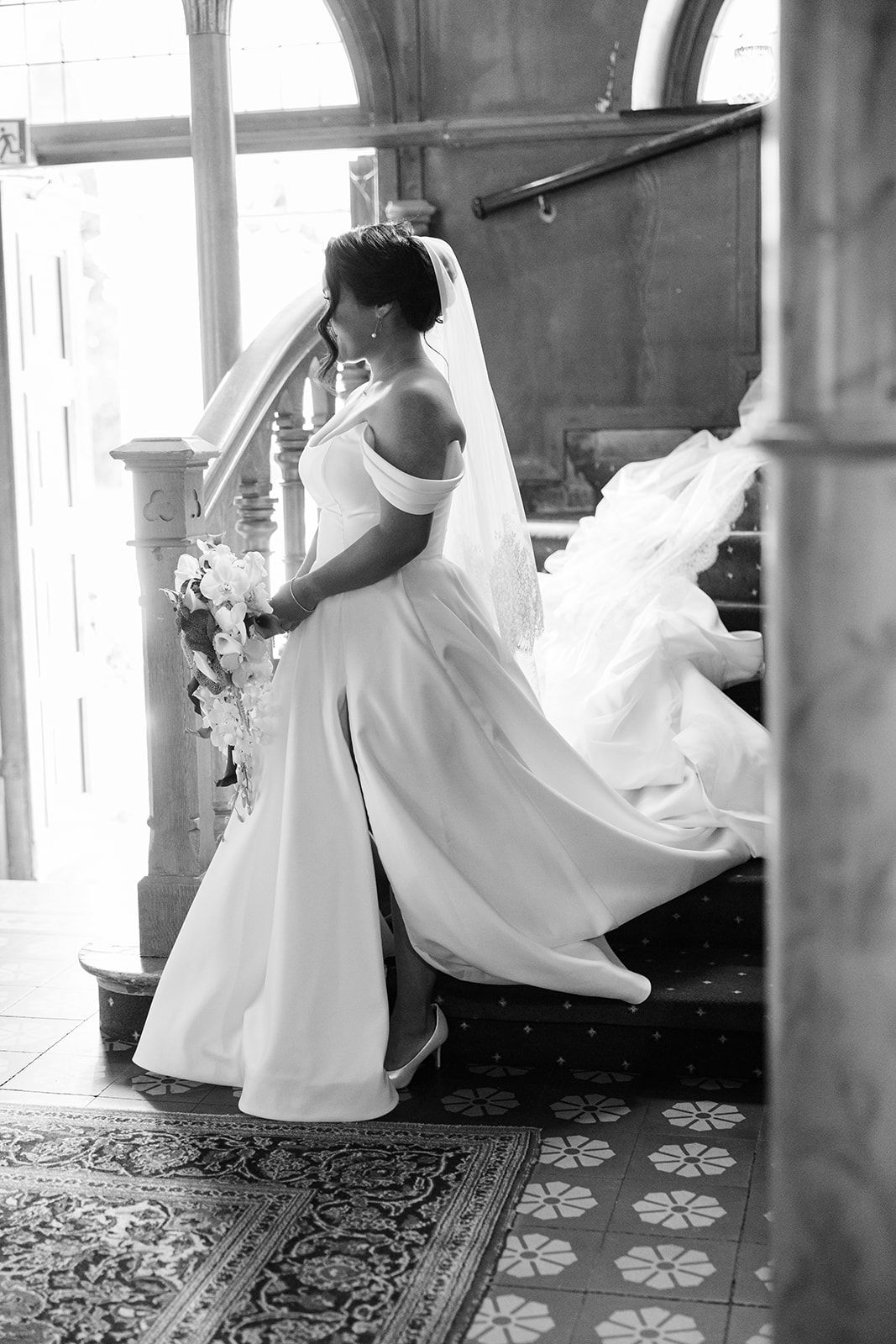 A black and white photograph shows a flowing white dress twirling in motion across a patterned floor.