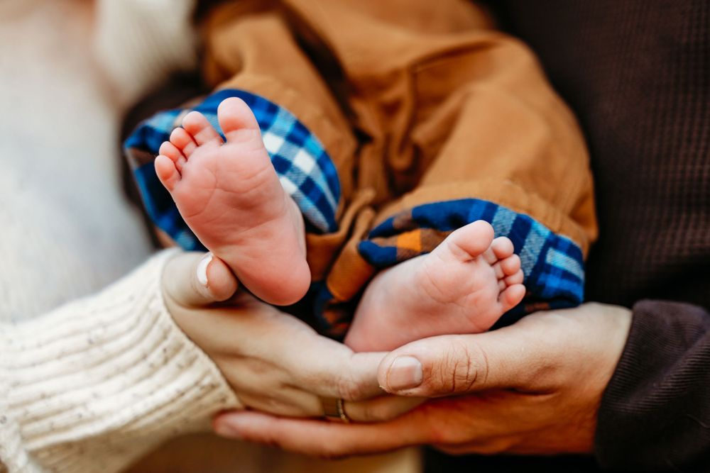 Close-up photos of tiny newborn baby feet being gently held by adult hands.
