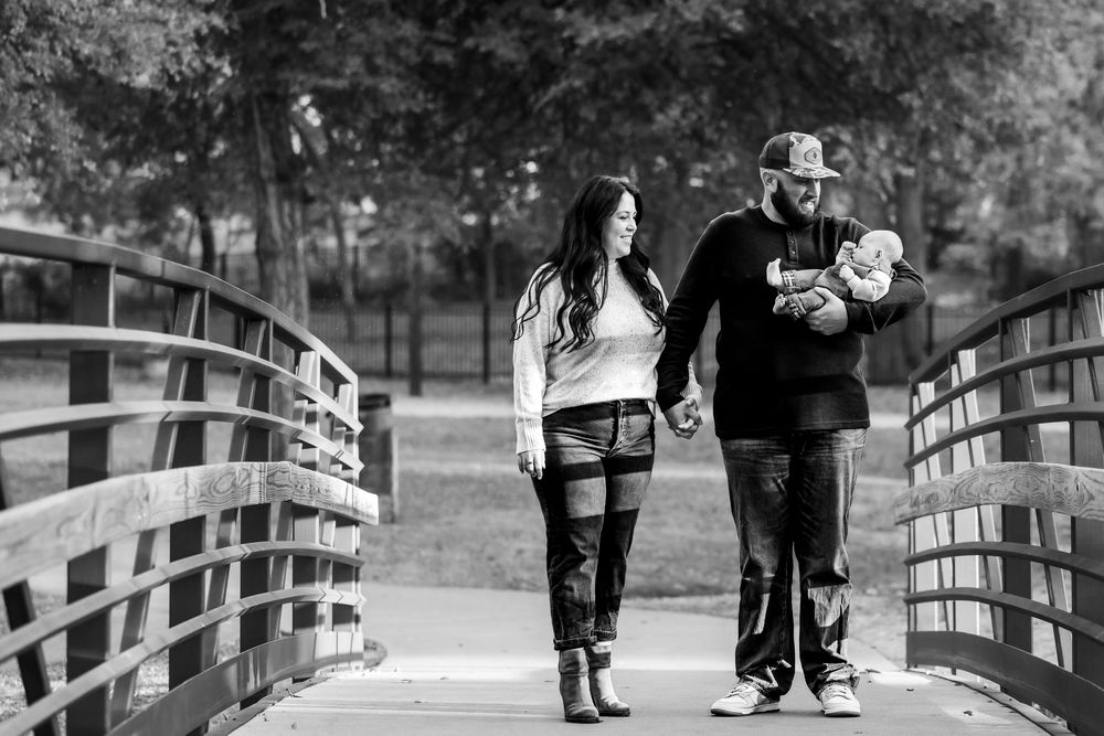 Black and white panoramic sequence showing people walking across a wooden bridge in a park setting.