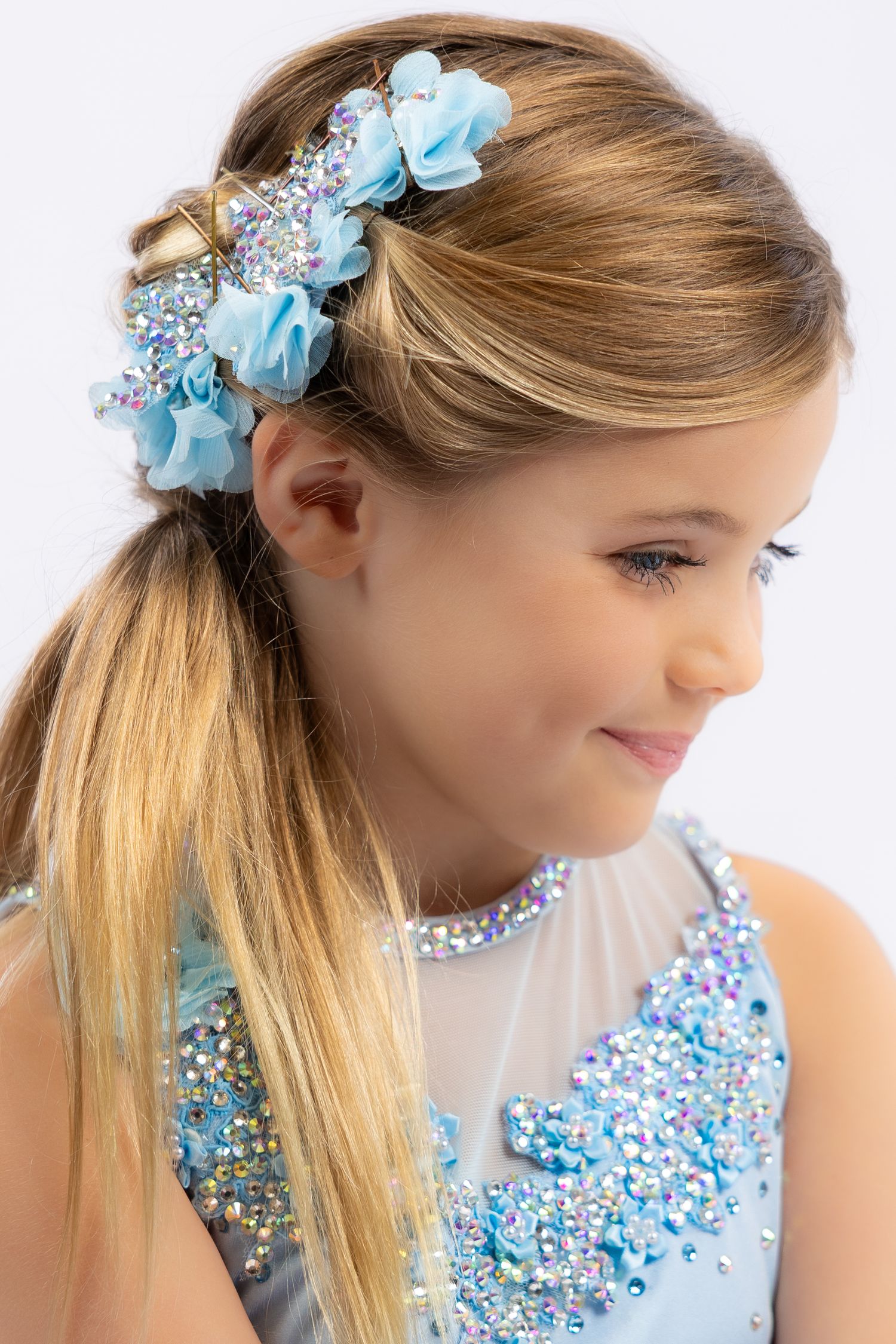 Side profile views showing blonde hair adorned with light blue floral hair accessory and beaded neckline detail.