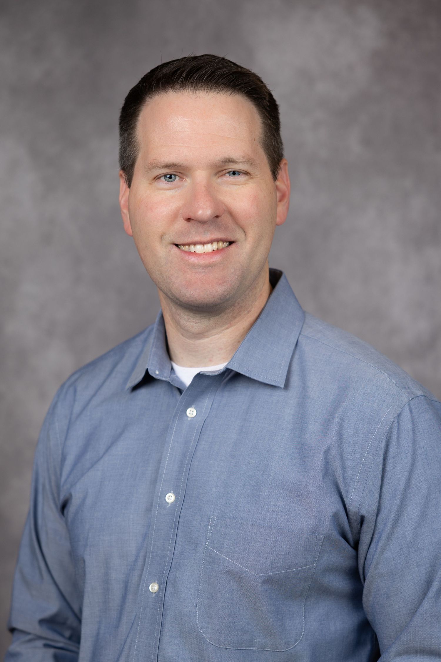 Professional headshot series showing person in blue dress shirt against gray background with warm smile.