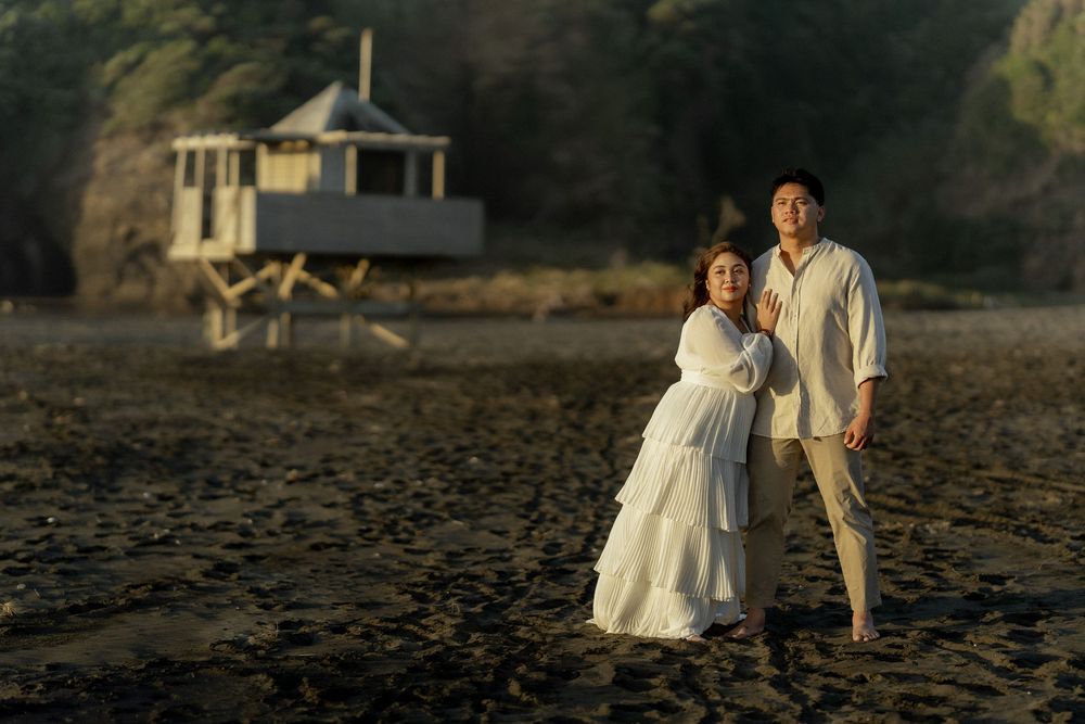 Romantic beach wedding couple walking along the shore at sunset with their reflections in the wet sand.