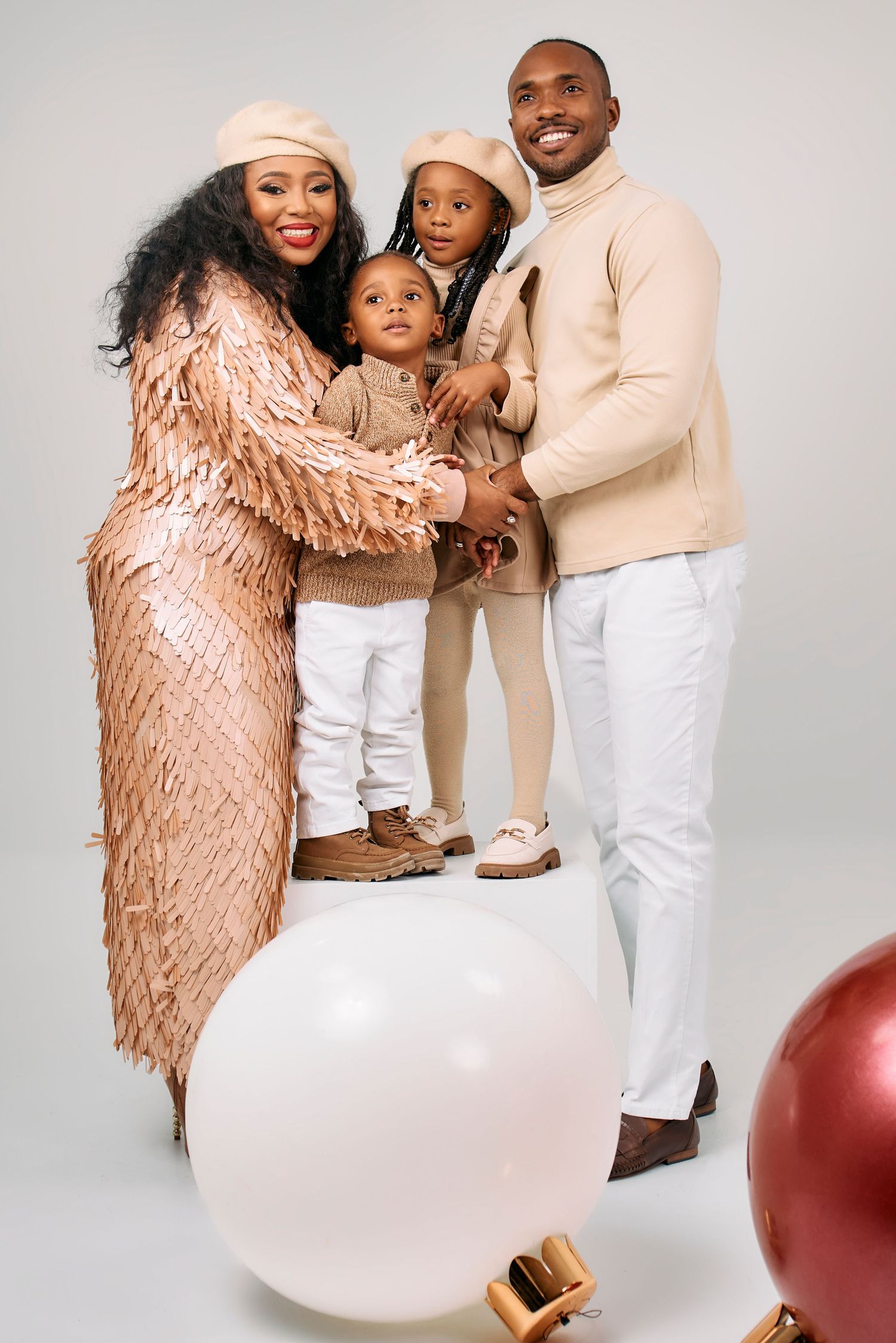 Studio family portrait with neutral tones and large white balloon decoration.