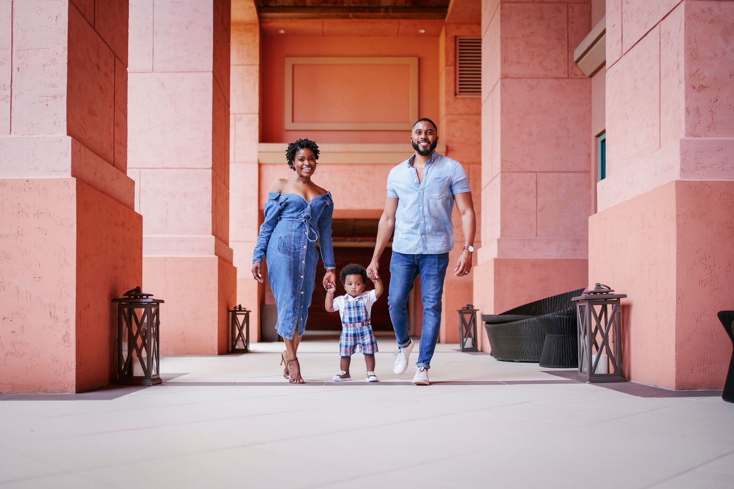 A young family walks together through a pink-colored hallway.