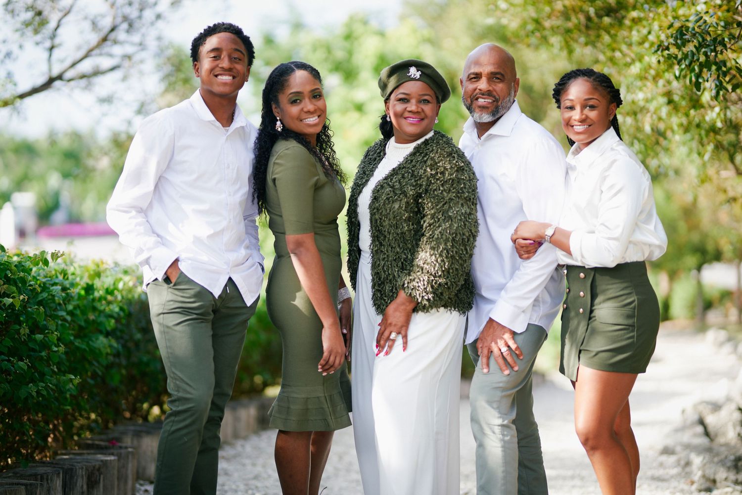 A stylish multi-generational family poses outdoors in coordinated outfits.