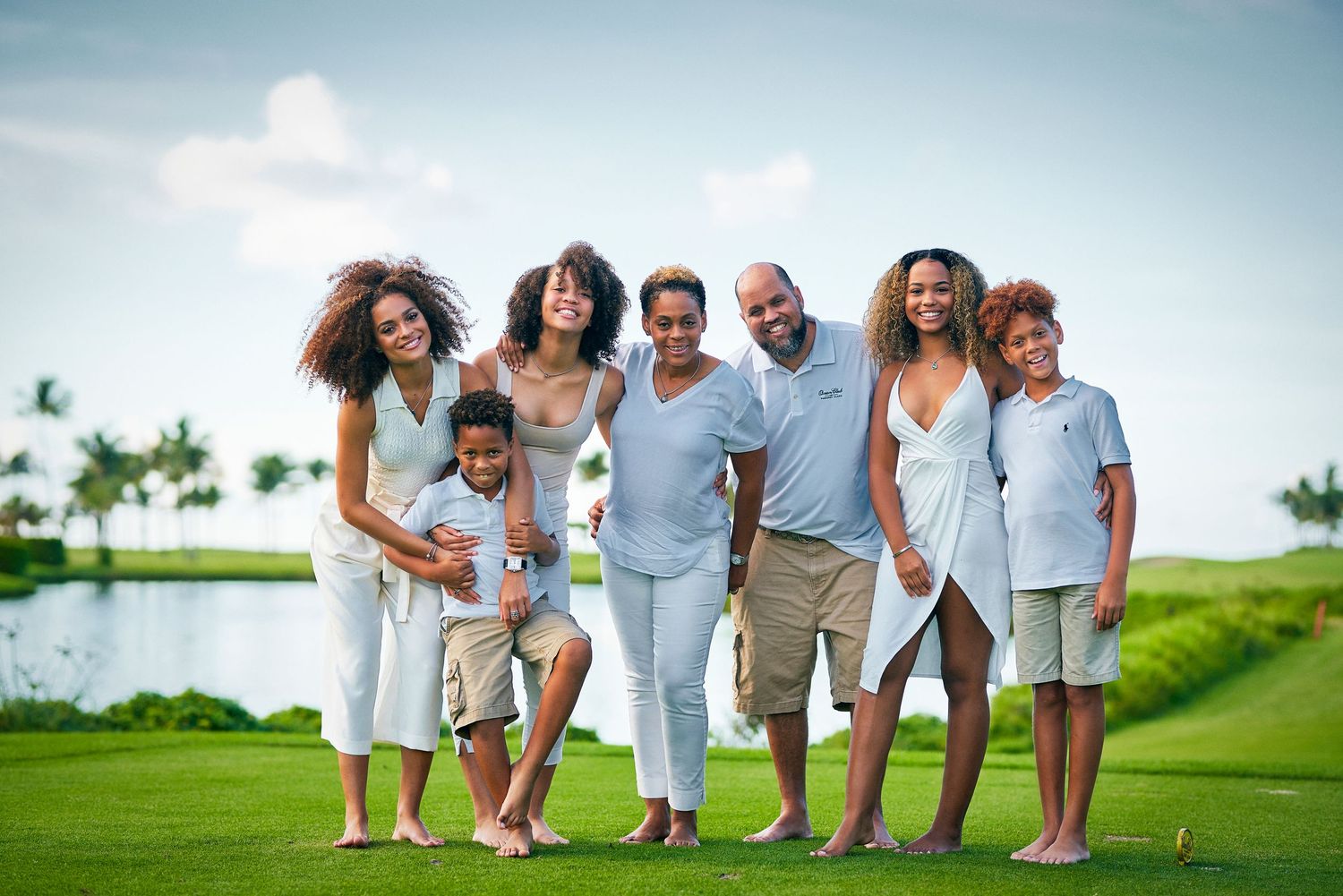 A cheerful family enjoys time together on a lush golf course by the water.