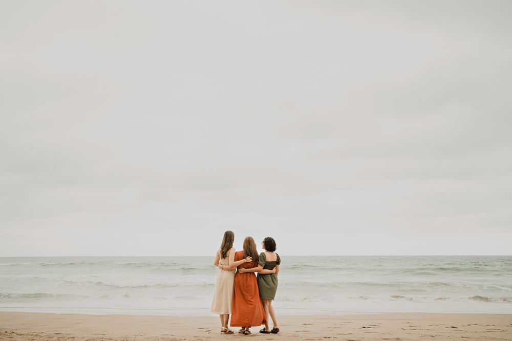 Mother and daughters looking at the ocean, with a cloudy sky