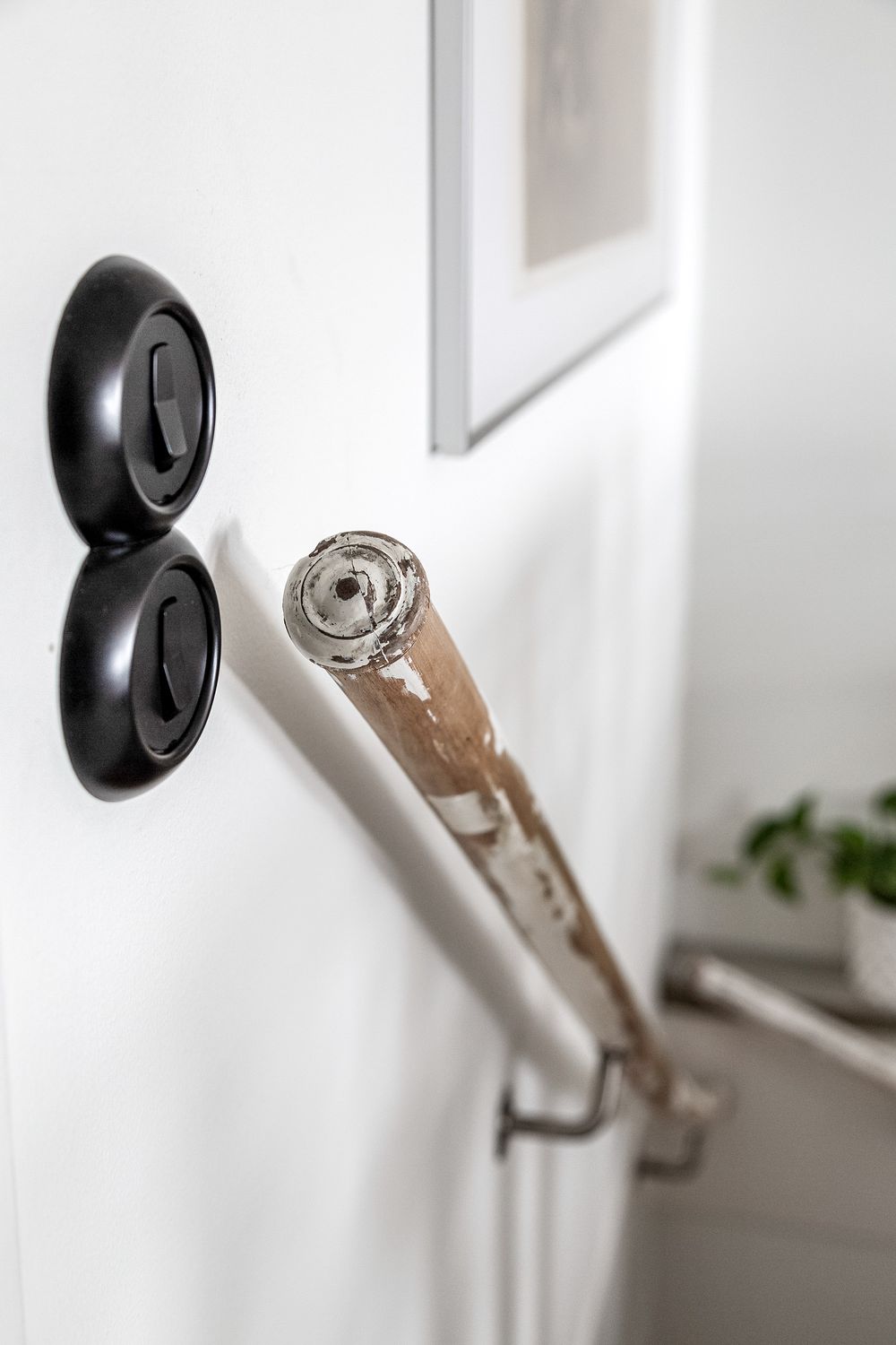 Close-up of black light switches and metallic door stopper on white wall.