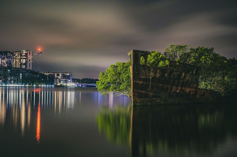 Nighttime waterfront scene with colorful light reflections on dark water.