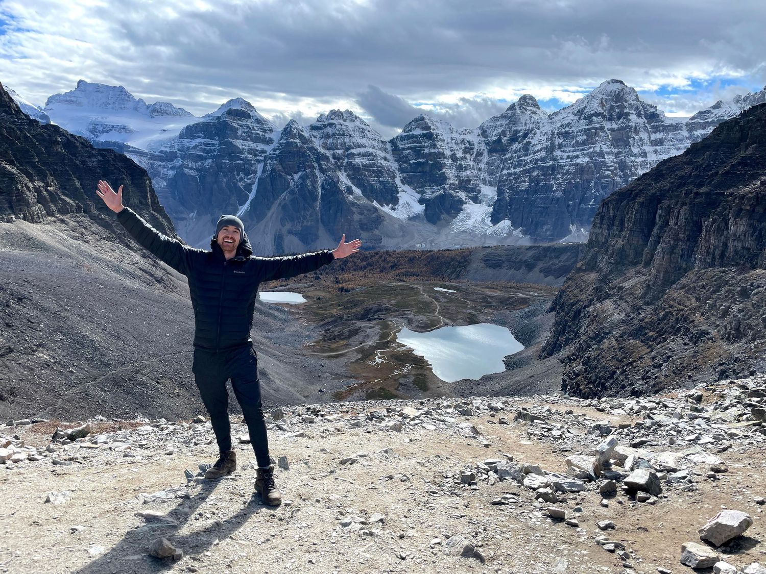 Photographer John Davis is seen with arms spread wide at the top of a mountain in Banff national park.