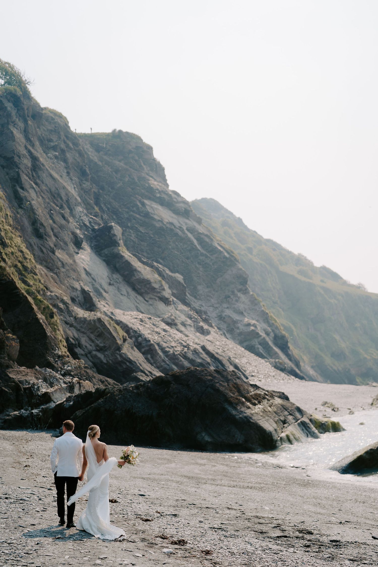 Bride and Groom walking along beach at Tunnels beach wedding venue in north devon