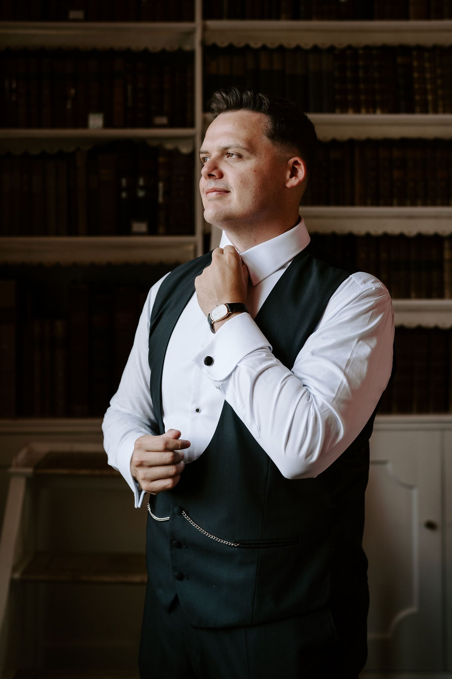 bride fixing shirt button in the library at Iscoyd park