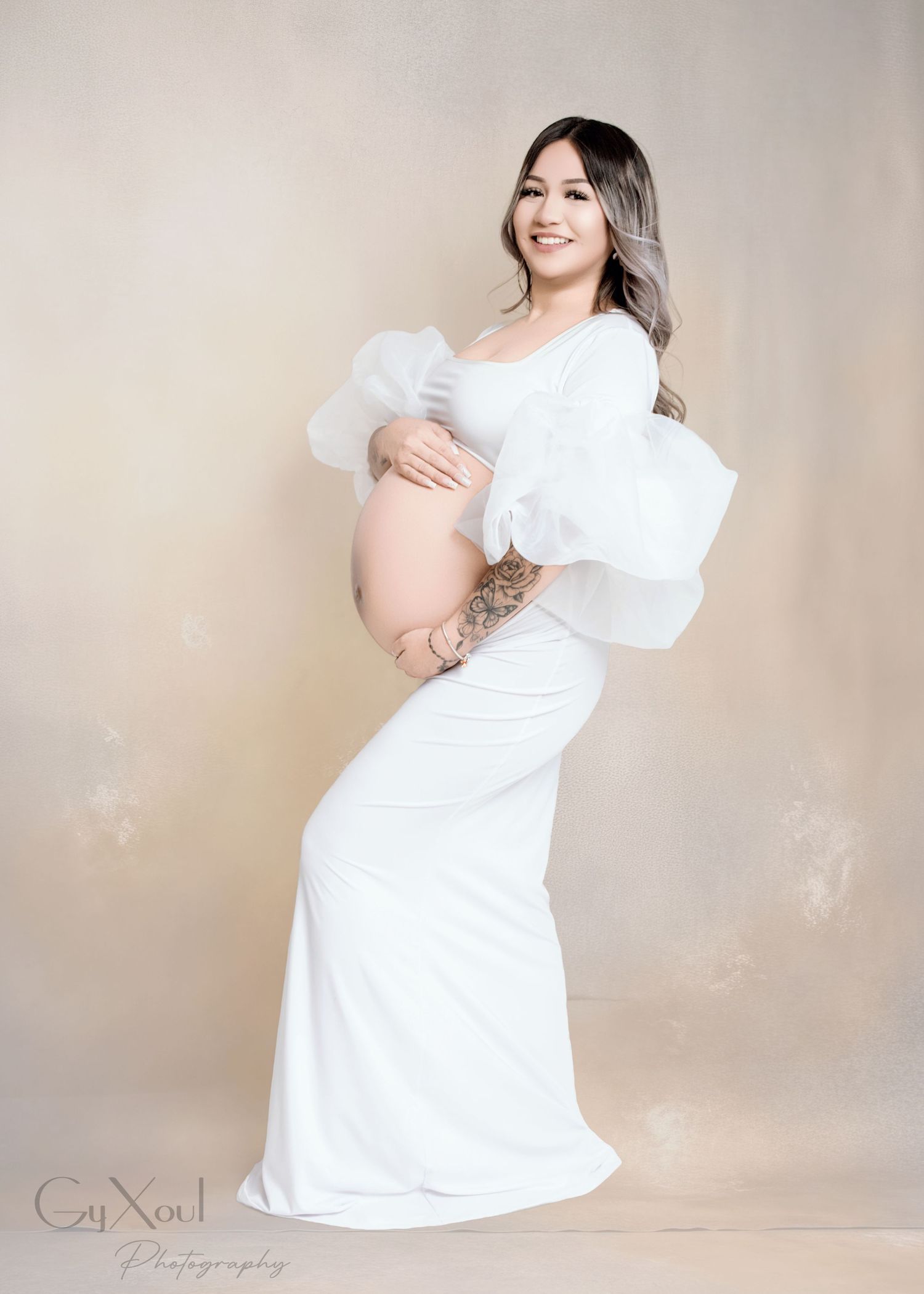 Maternity photo featuring woman in white dress with dramatic puffy sleeves.