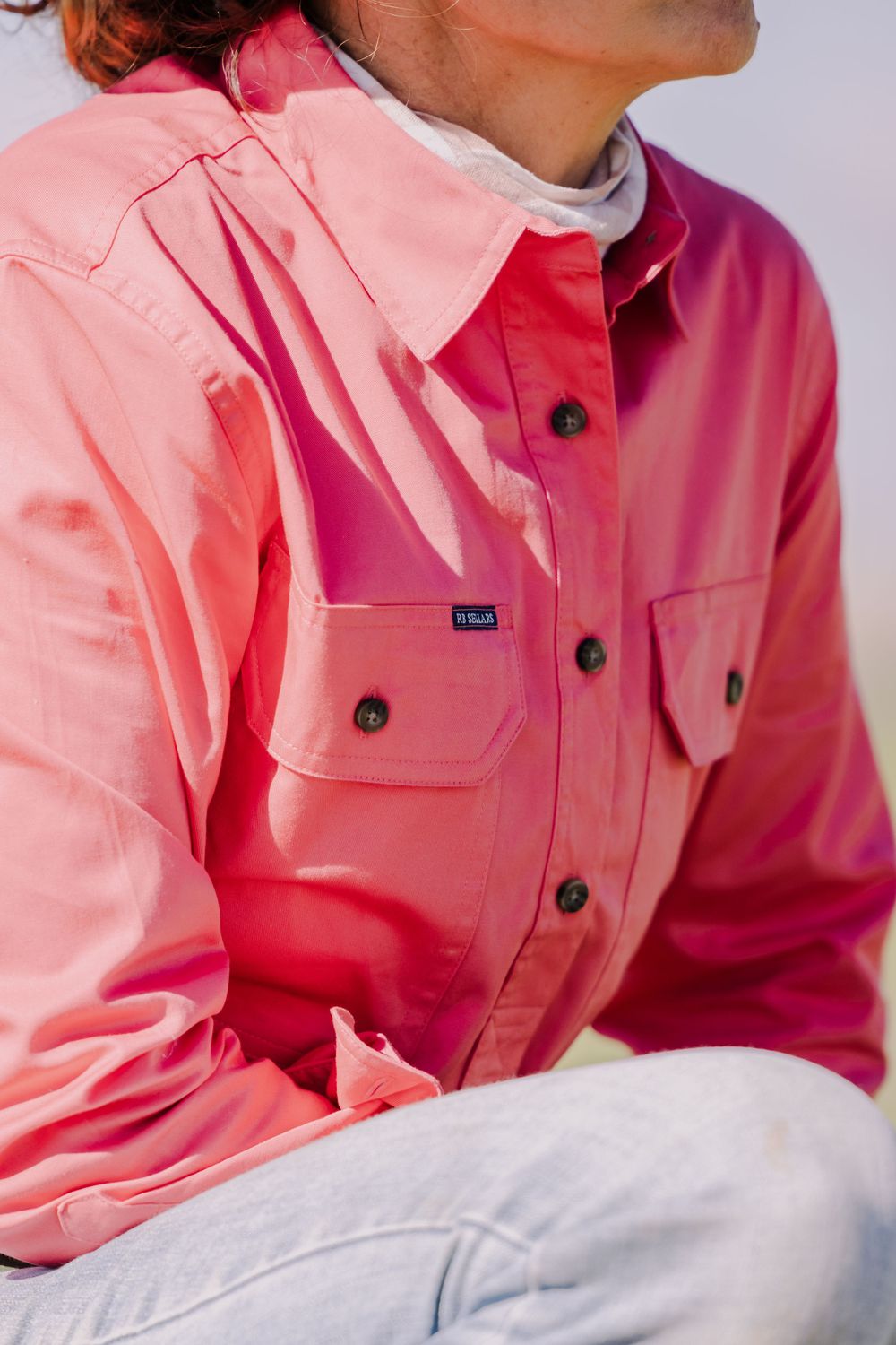 Close-up of a pink button-up work shirt with utility pockets.