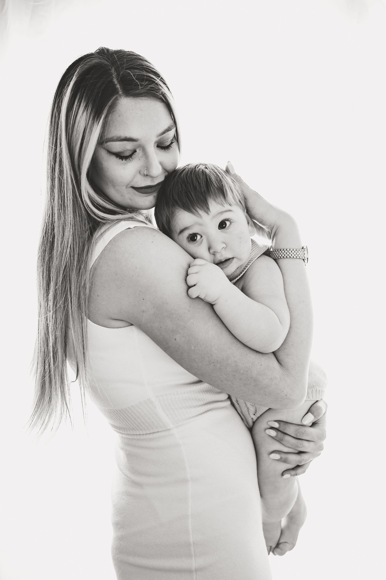 Black and white portrait of parent and young child embracing against white background.