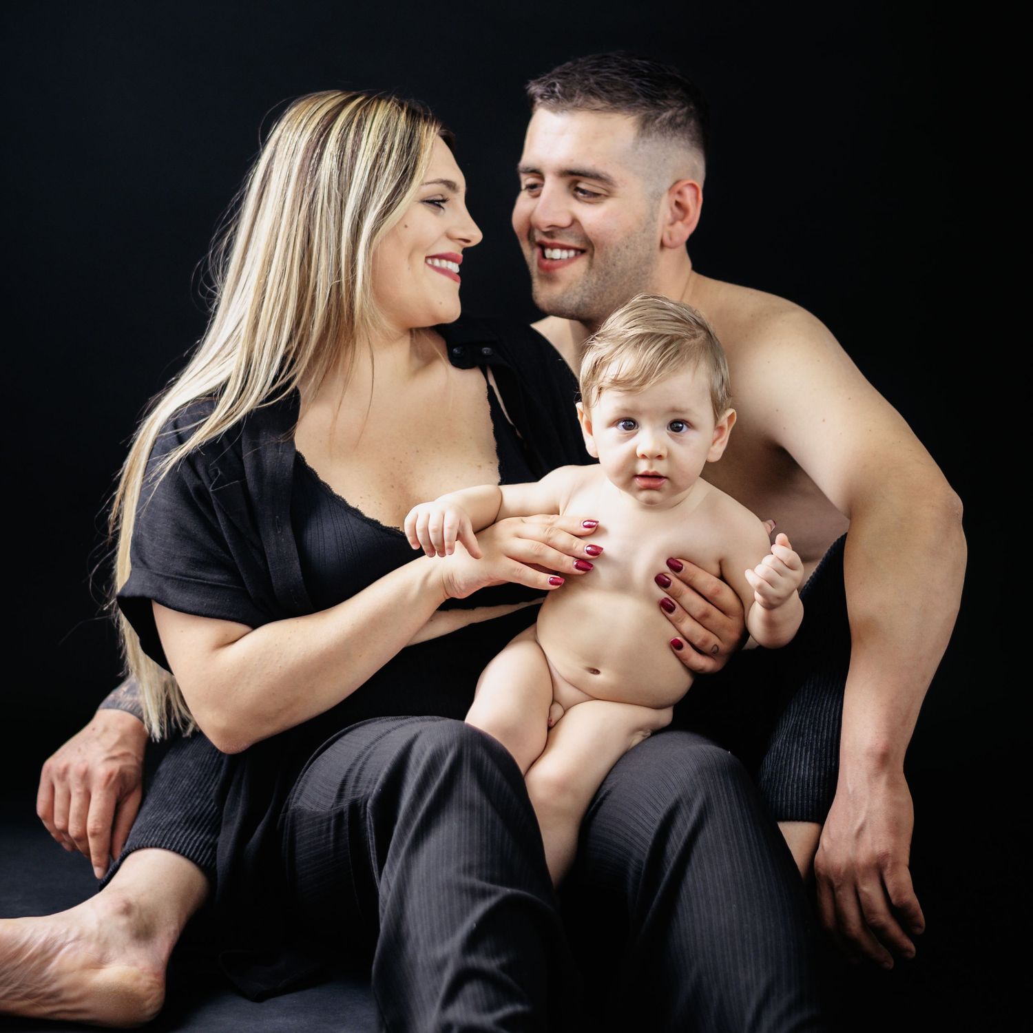 Intimate family portrait against black background showing joyful interaction.