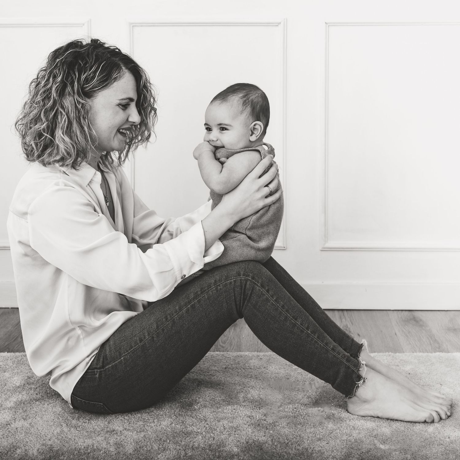Black and white portrait of a tender parenting moment on a carpeted floor.