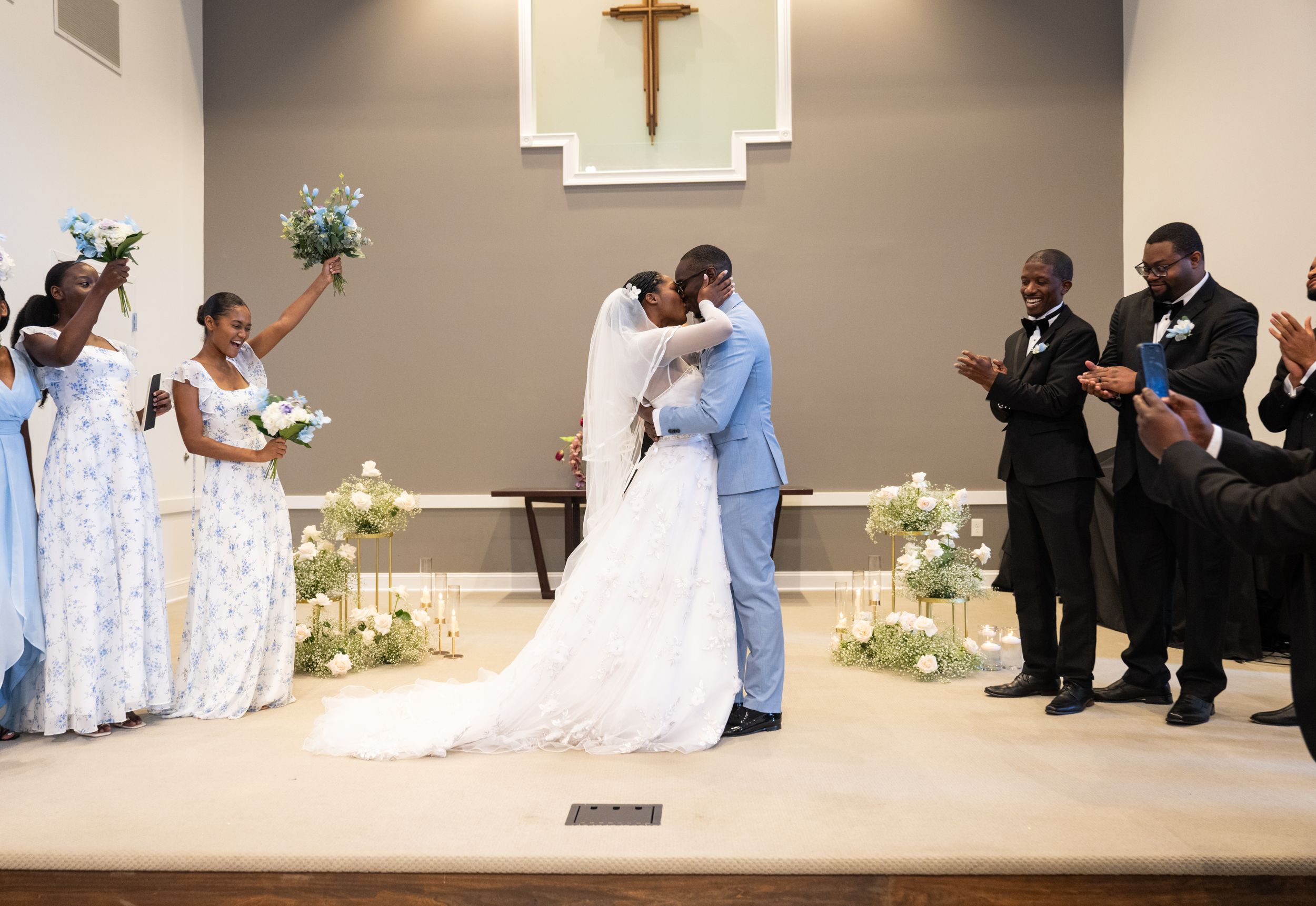 A wedding ceremony takes place in a church with attendants in blue and white attire.