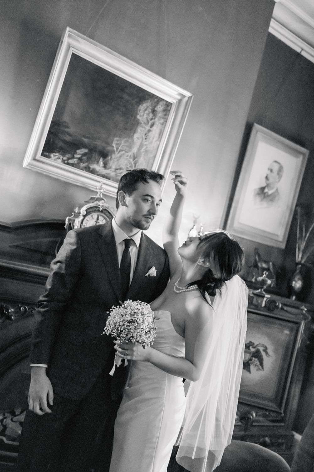 A classic black and white wedding portrait in an elegant room with framed artwork.