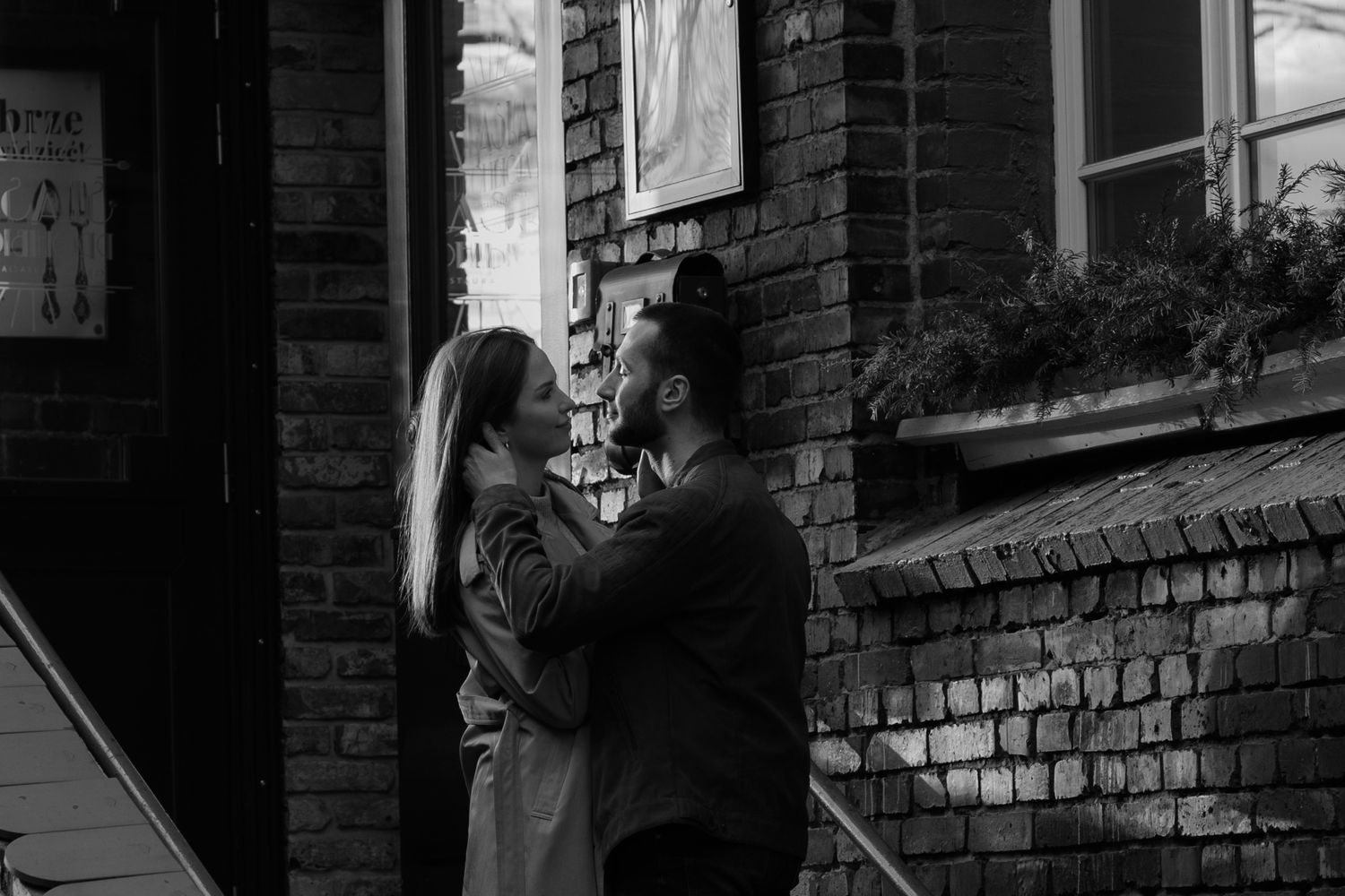 A romantic black and white moment between two people on brick steps in front of a building.