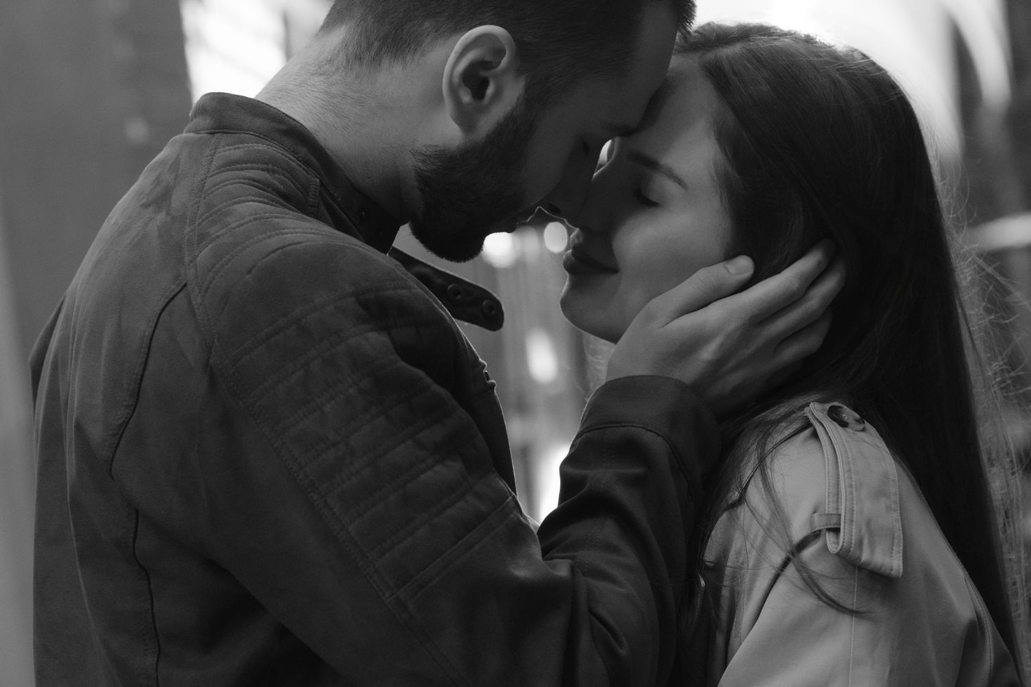 Black and white intimate photo of a romantic couple in tender embrace with foreheads touching.