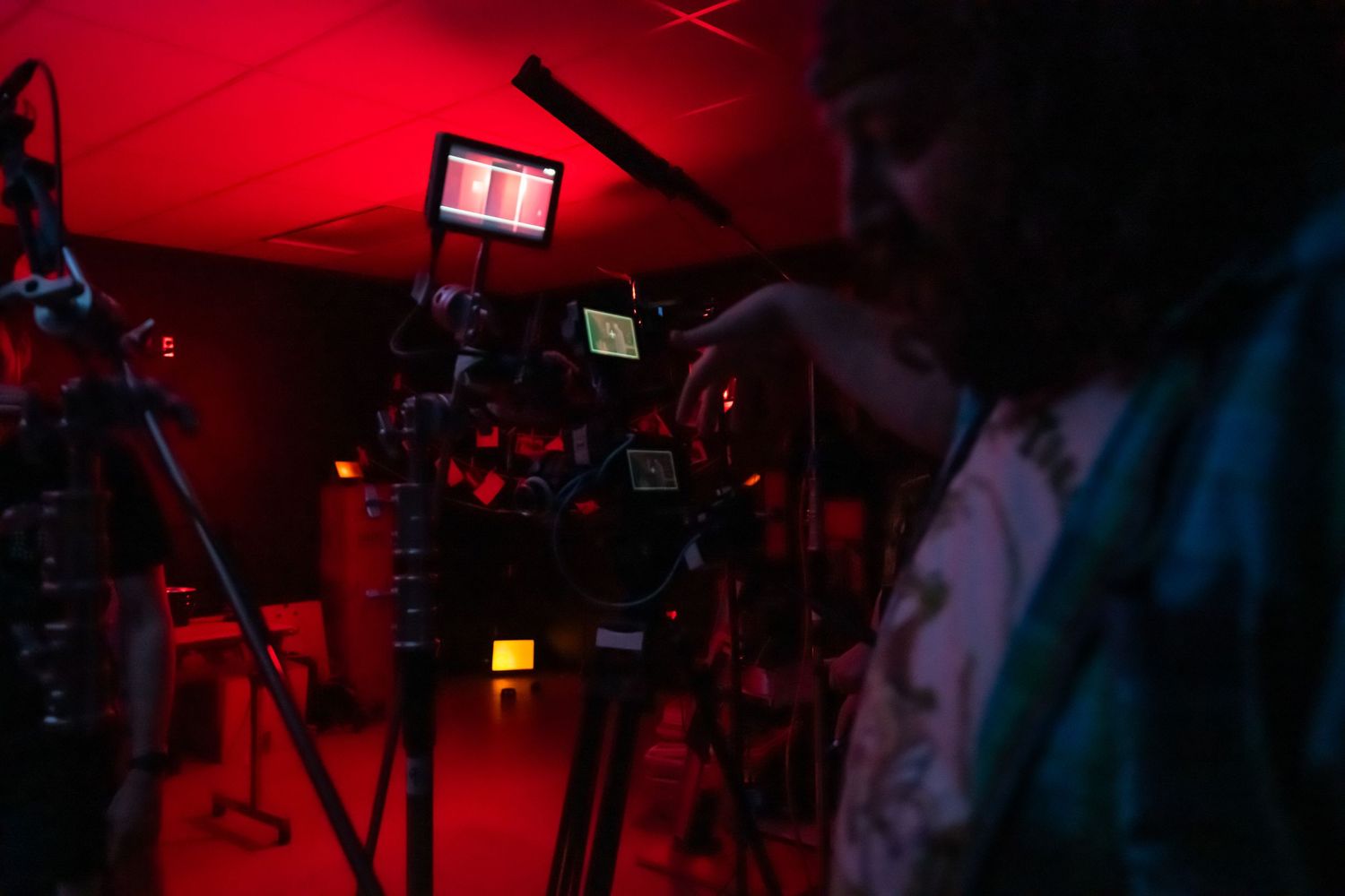 Cinematographer operating a professional camera on a red-lit film production set.