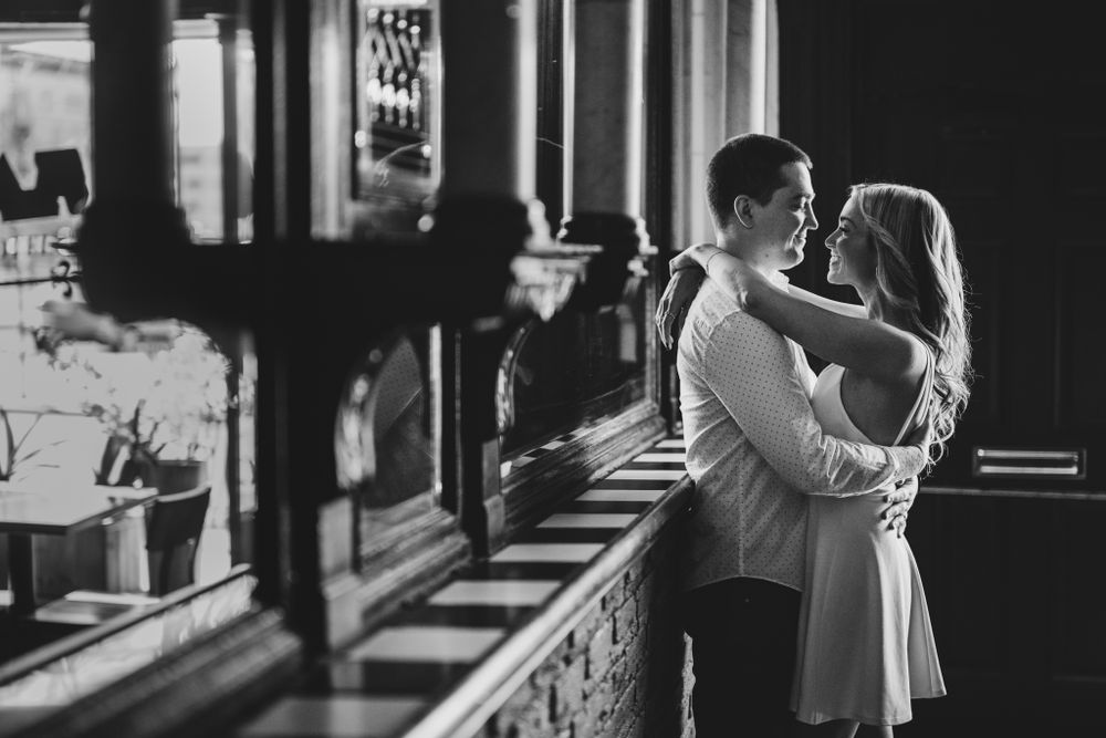 Silhouetted couple embracing in front of window with dramatic lighting.
