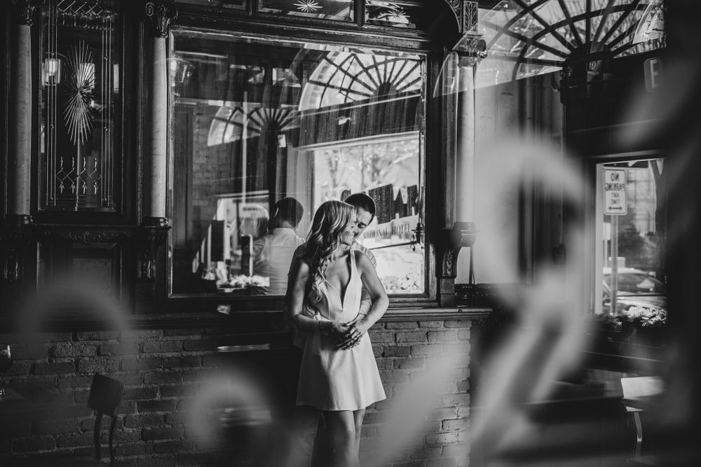 Black and white photo of couple in vintage bar interior with dramatic lighting.