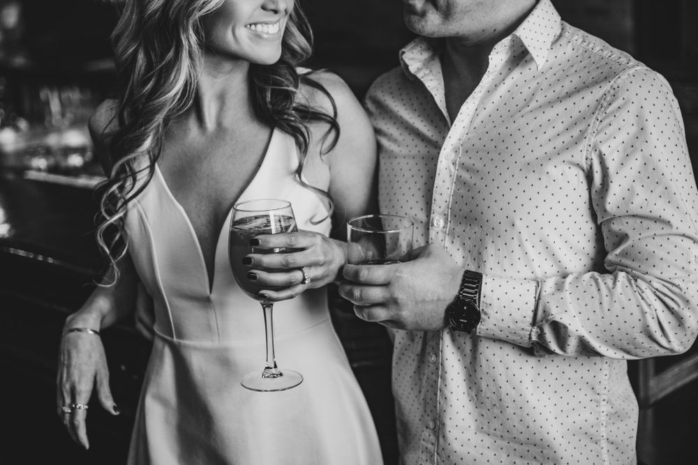 Couple holding wine glasses while sharing intimate moment in bar setting.
