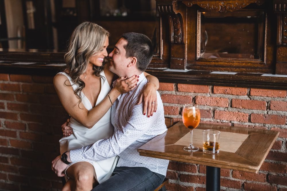 Intimate moment shared between couple at a dimly lit bar with cocktails.