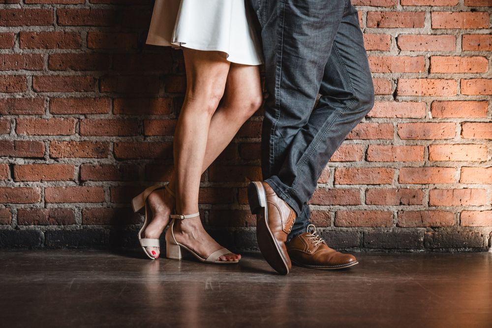 Close-up of formal footwear against brick wall showing contrasting dress shoes.