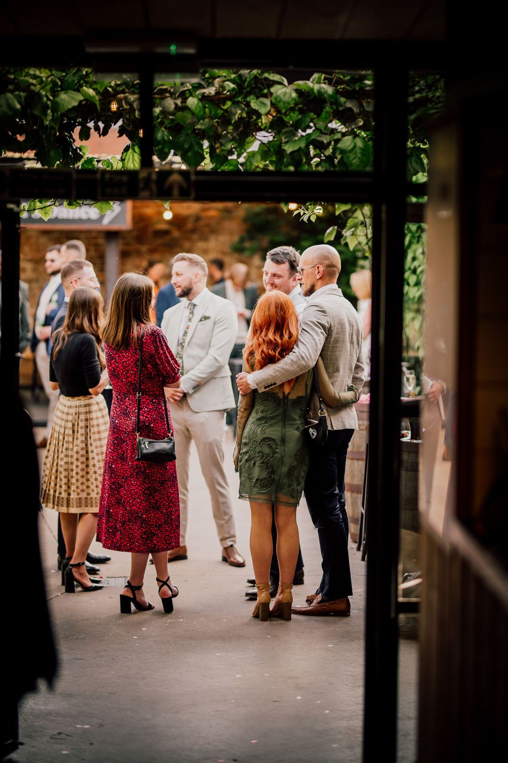 A group of people gathered at an outdoor event viewed through dark window frames.