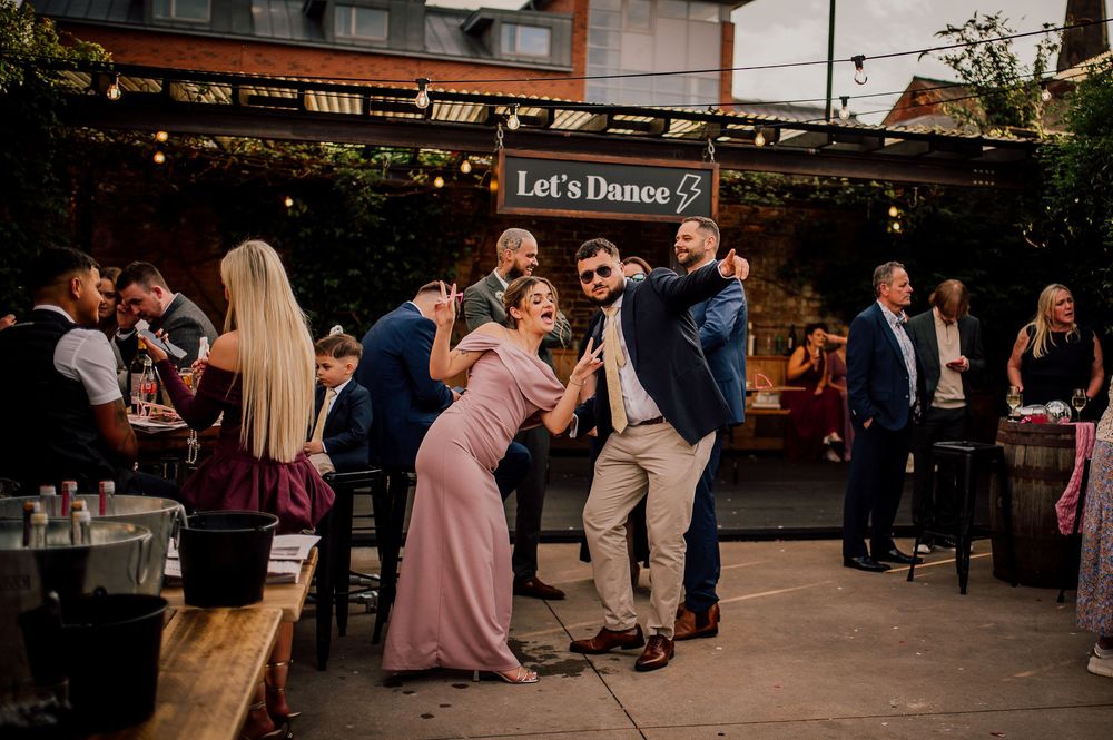 People dancing and celebrating at an outdoor restaurant patio during a festive evening gathering.