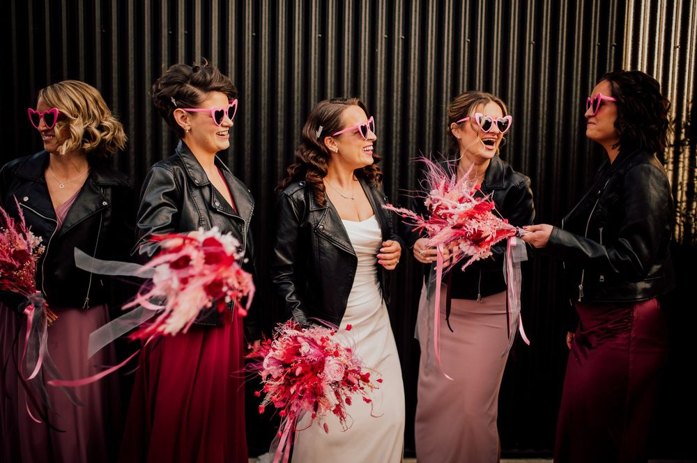 A group of people in formal attire laughing and celebrating with pink feather boas at an elegant evening event.