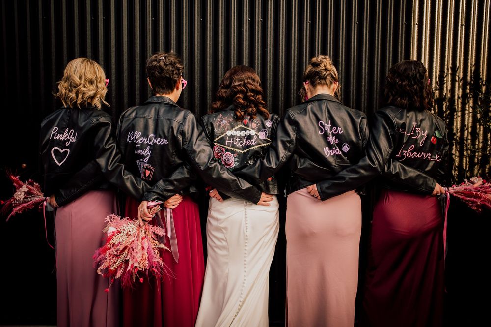 A row of people wearing formal attire stand with their backs to the camera at an event.