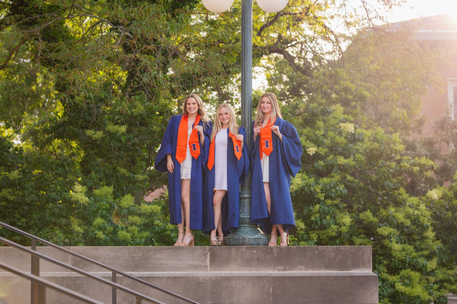 Group of three students holding their UIUC logo up at Foellinger Auditorium
