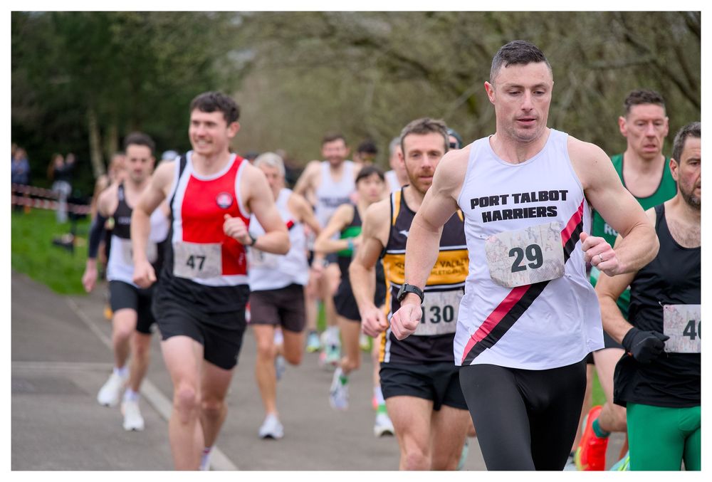 Runner wearing Port Talbot Harriers vest number 29 leads group of athletes in outdoor road race.