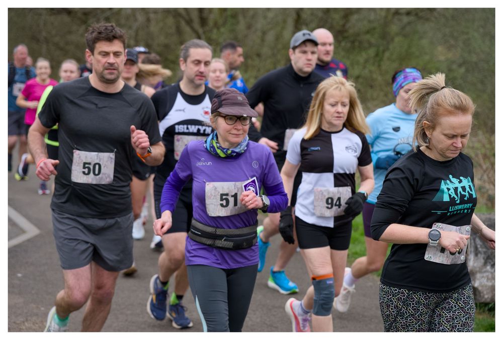 Group of runners wearing numbered bibs including 50, 51, and 94 competing in outdoor road race.