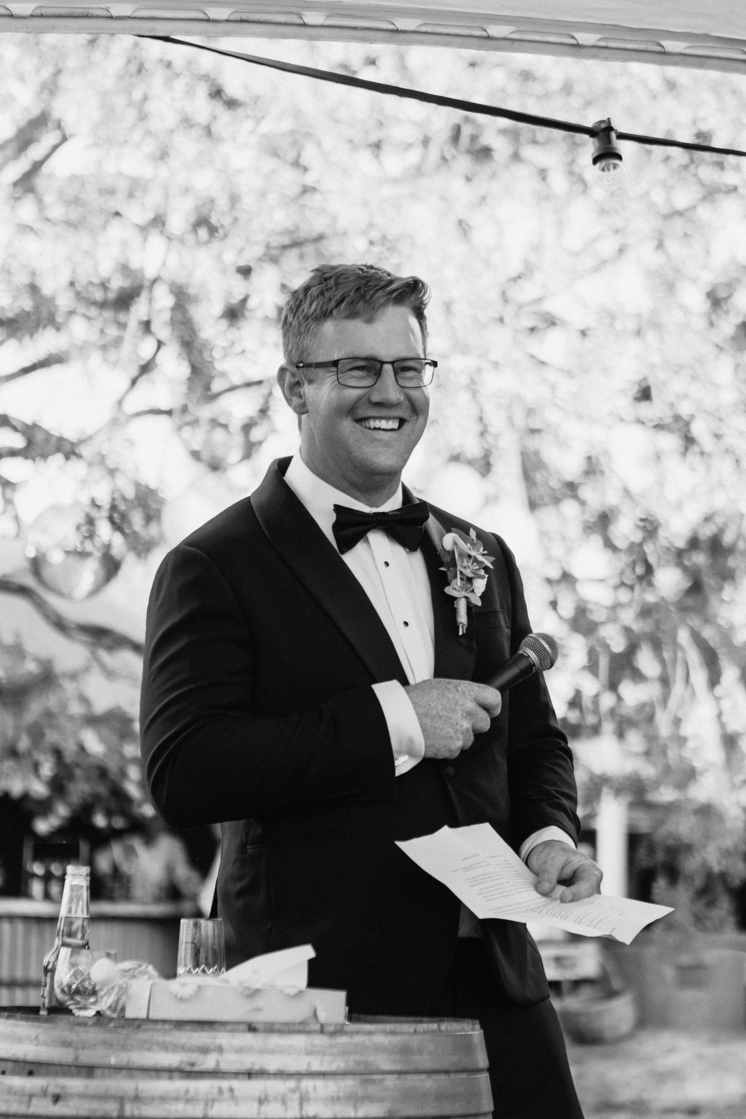 Best man laughing during speech at reception of country wedding