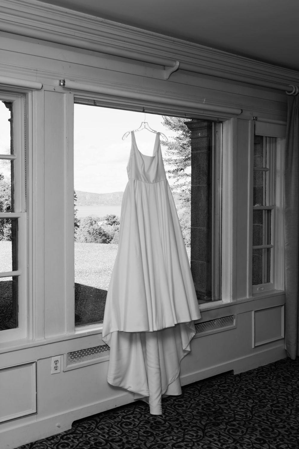 A series of white ghost-like figures hanging in front of windows in a dark carpeted hallway creates an eerie atmosphere.